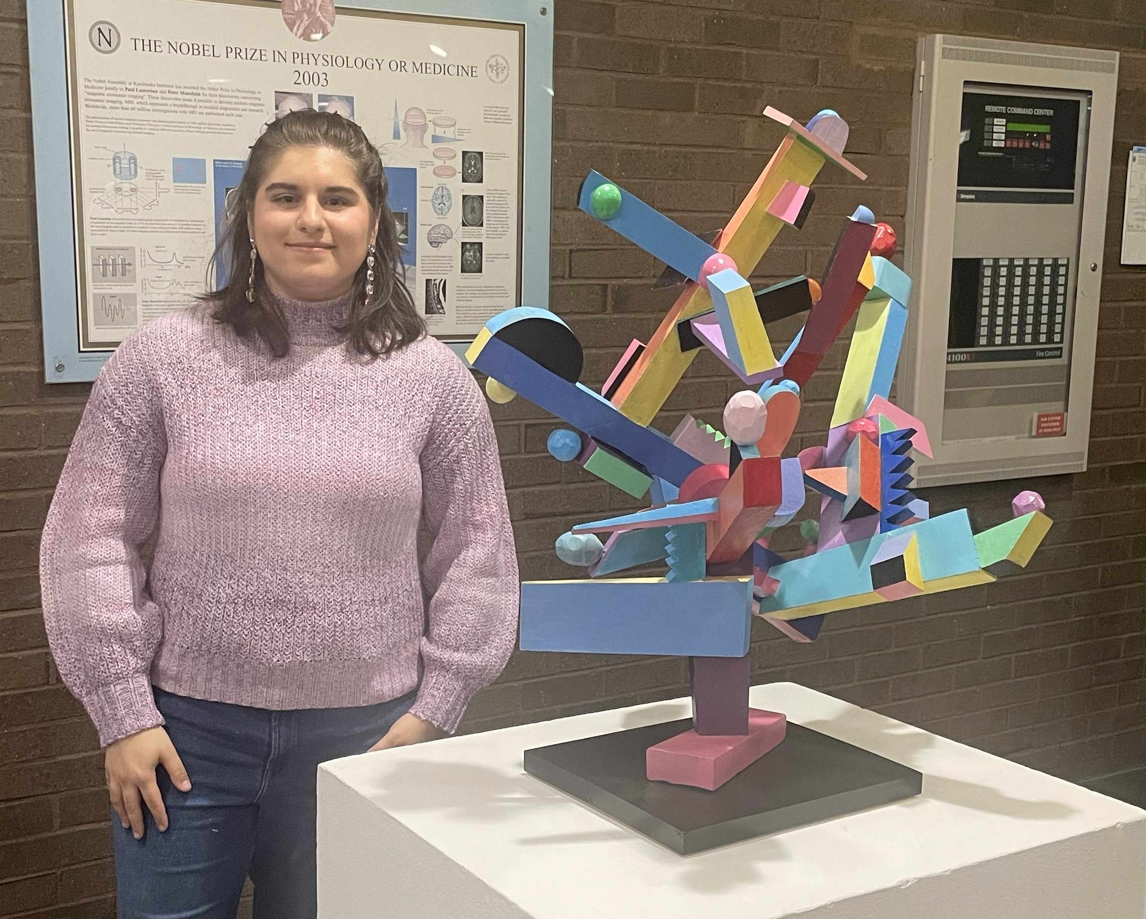 Kyla Hutter Female student at Stonybrook Brook University poses next to colorful art sculpture