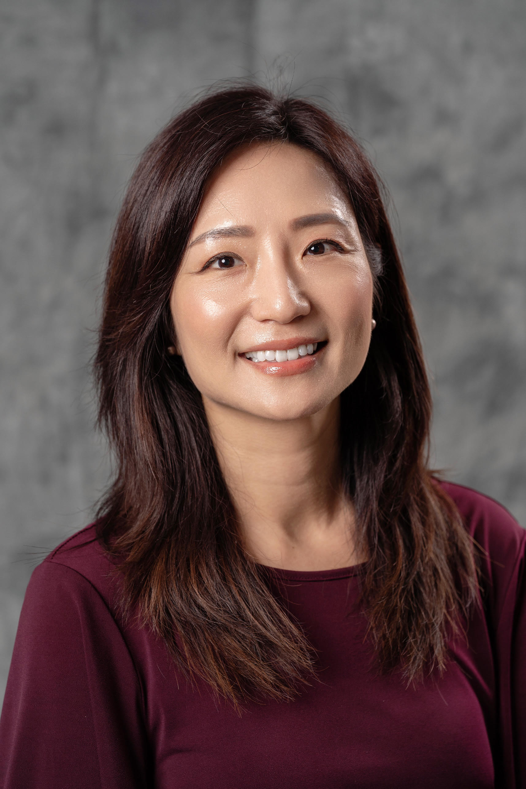 Ming Huang, with shoulder-length dark brown hair  wearing a red sweater 