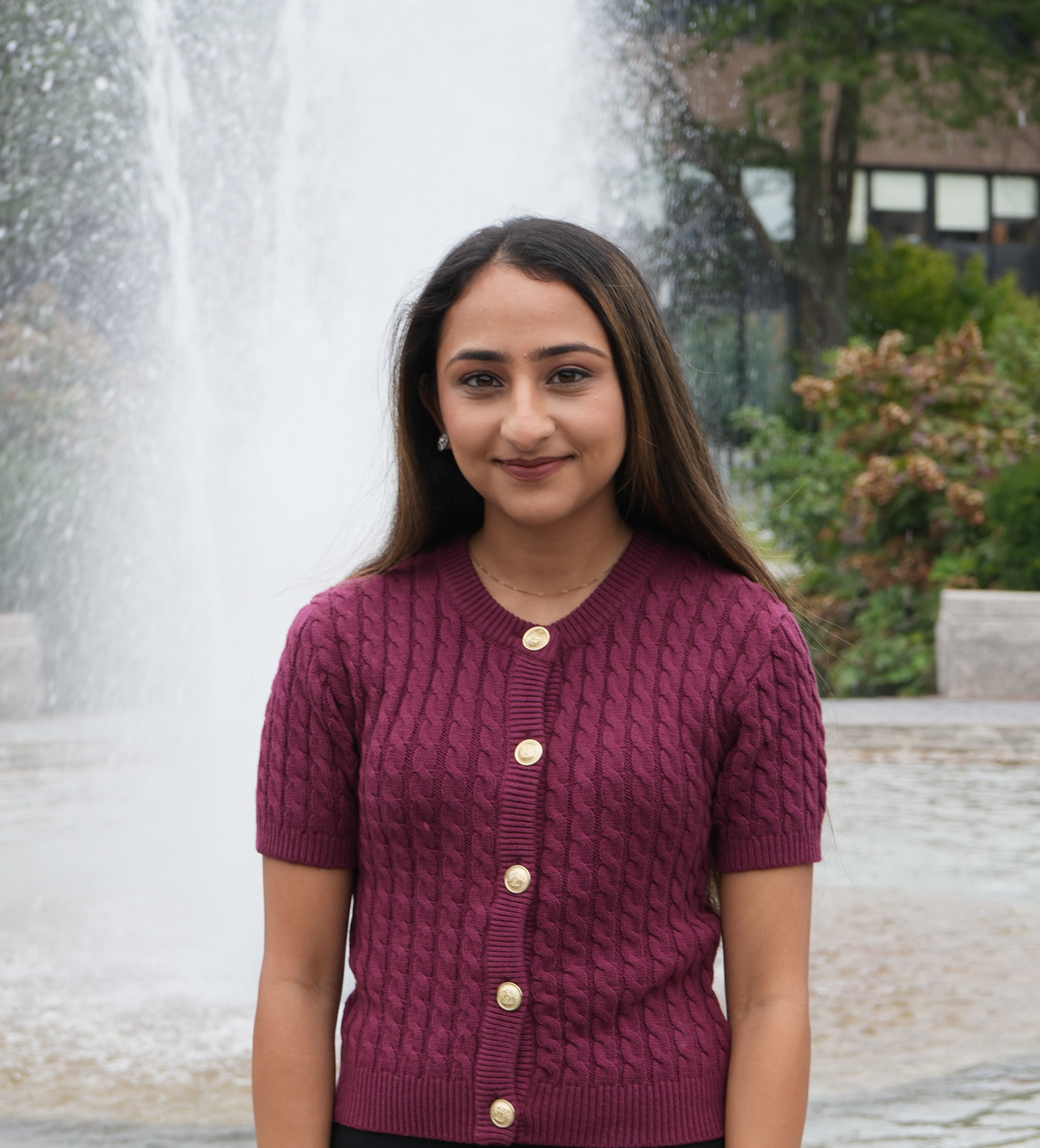 Laiba Rajput Person in a burgundy sweater standing in front of a fountain.