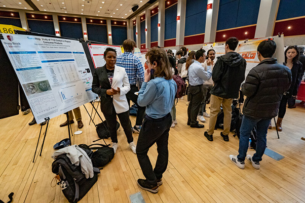 A crowded scientific conference hall with diverse attendees discussing research posters. The atmosphere is energetic, collaborative, and focused.