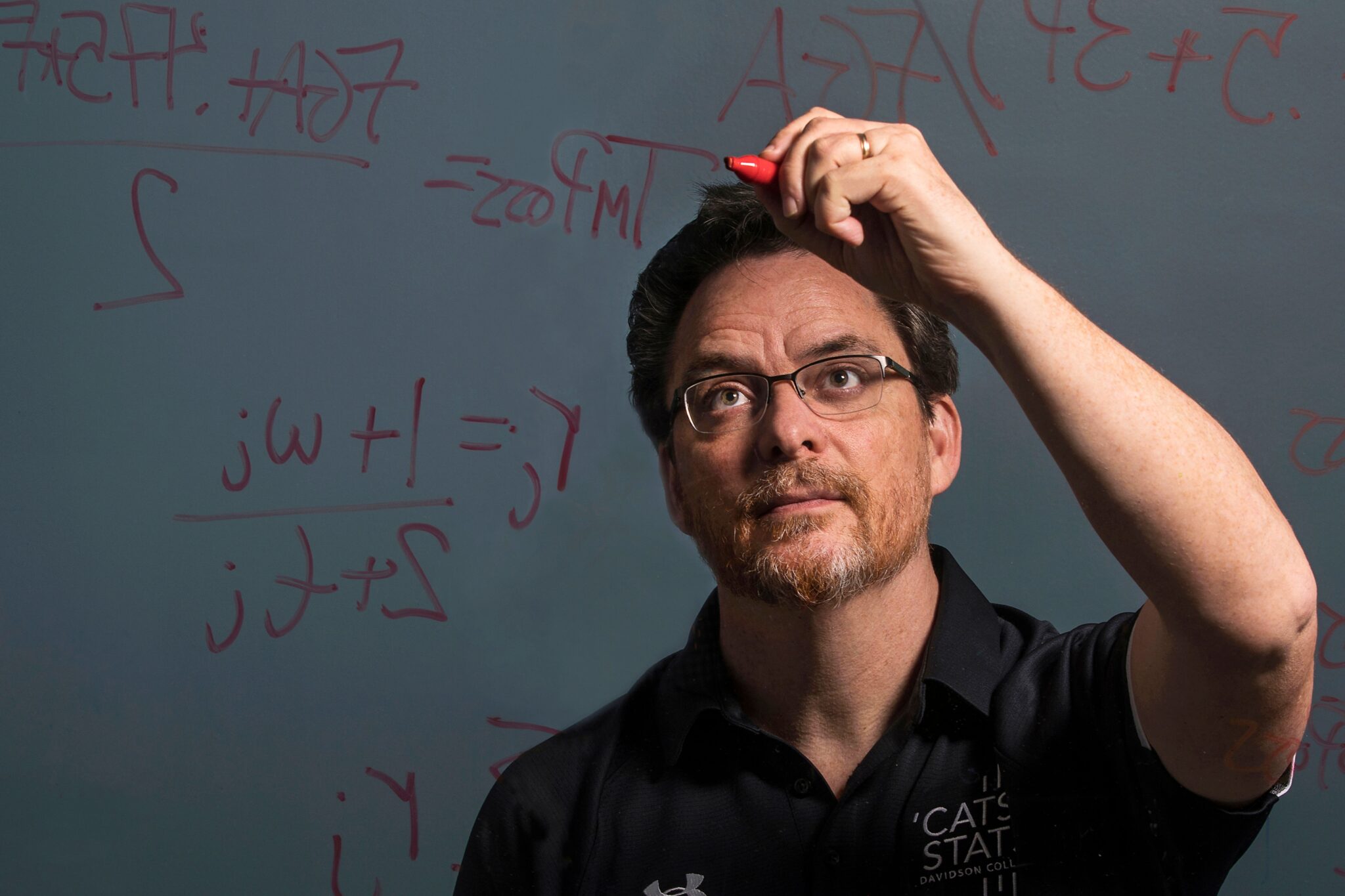 Tim Chartier solving a math problem on a clear board